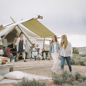 Group of friends enjoying an outdoor meal, a tent in the background.